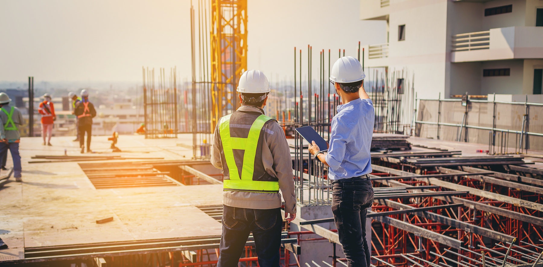 Structural engineer and foreman worker with touch pad discuss, plan working for the outdoors building construction site.