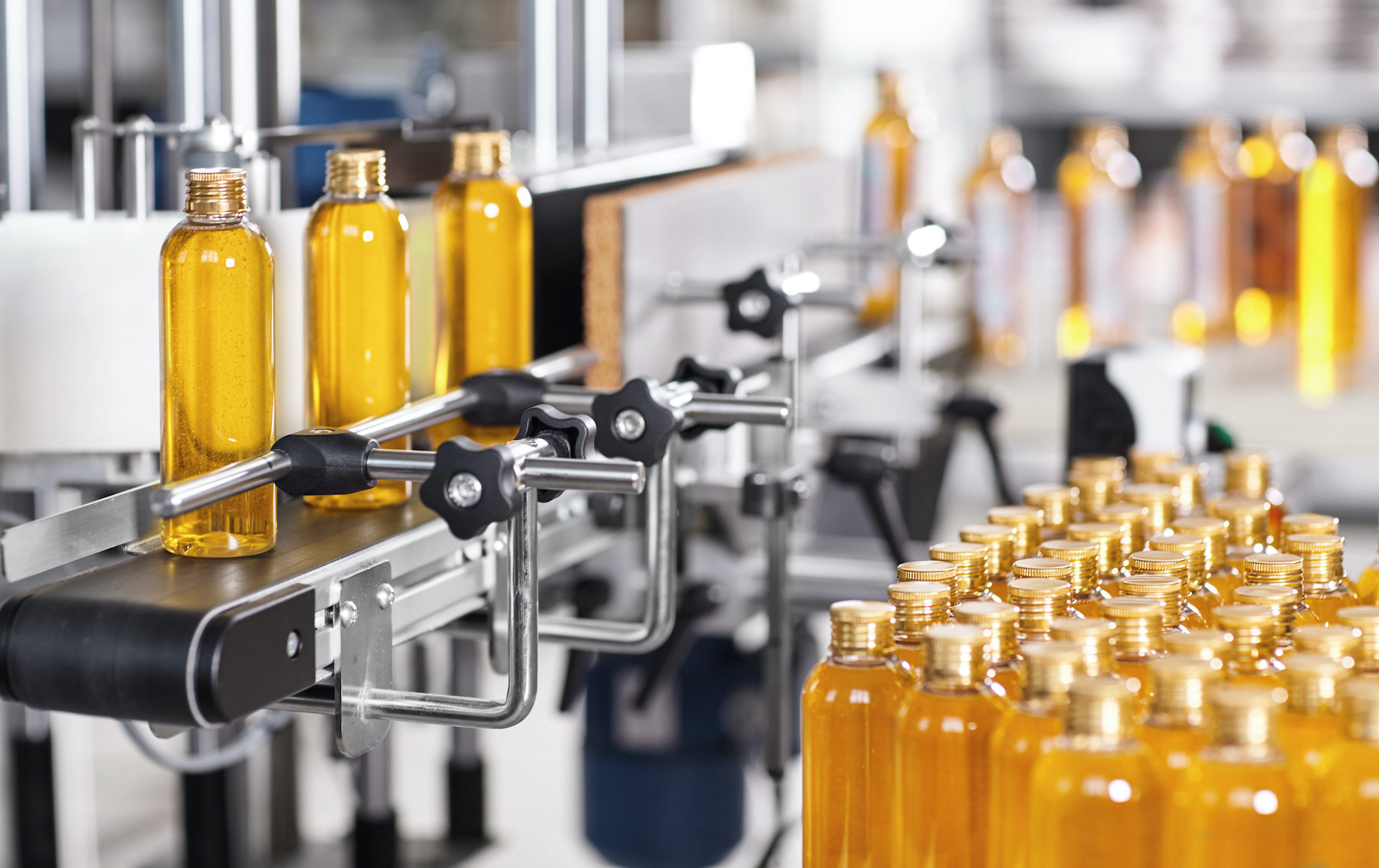 Production line of beauty and healthcare products at plant or factory. Process of manufacturing and packaging cosmetics goods. Glass or plastic bottles with screw caps standing on conveyor belt