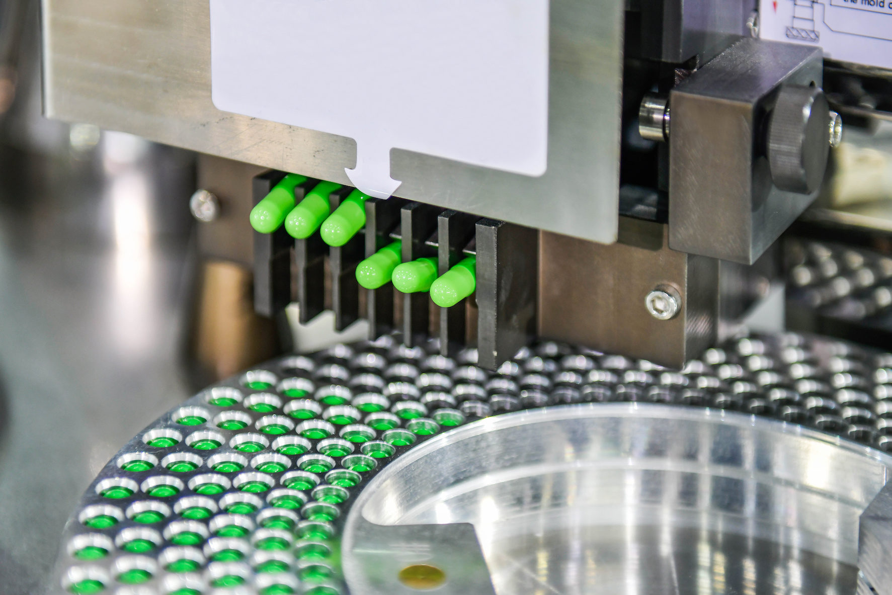 Green capsule medicine pill production line, Industrial pharmaceutical concept.