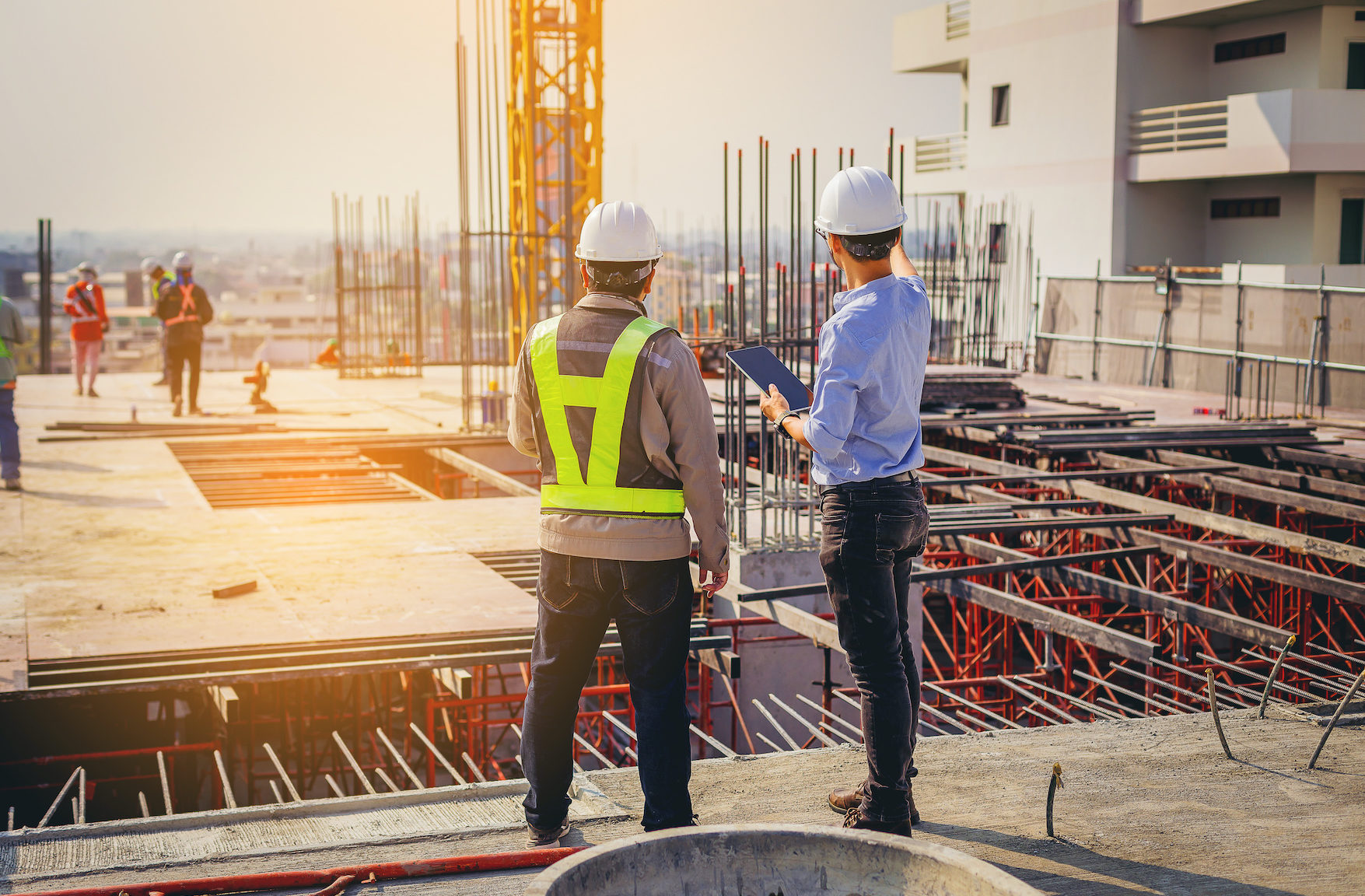 Structural engineer and foreman worker with touch pad discuss, plan working for the outdoors building construction site.