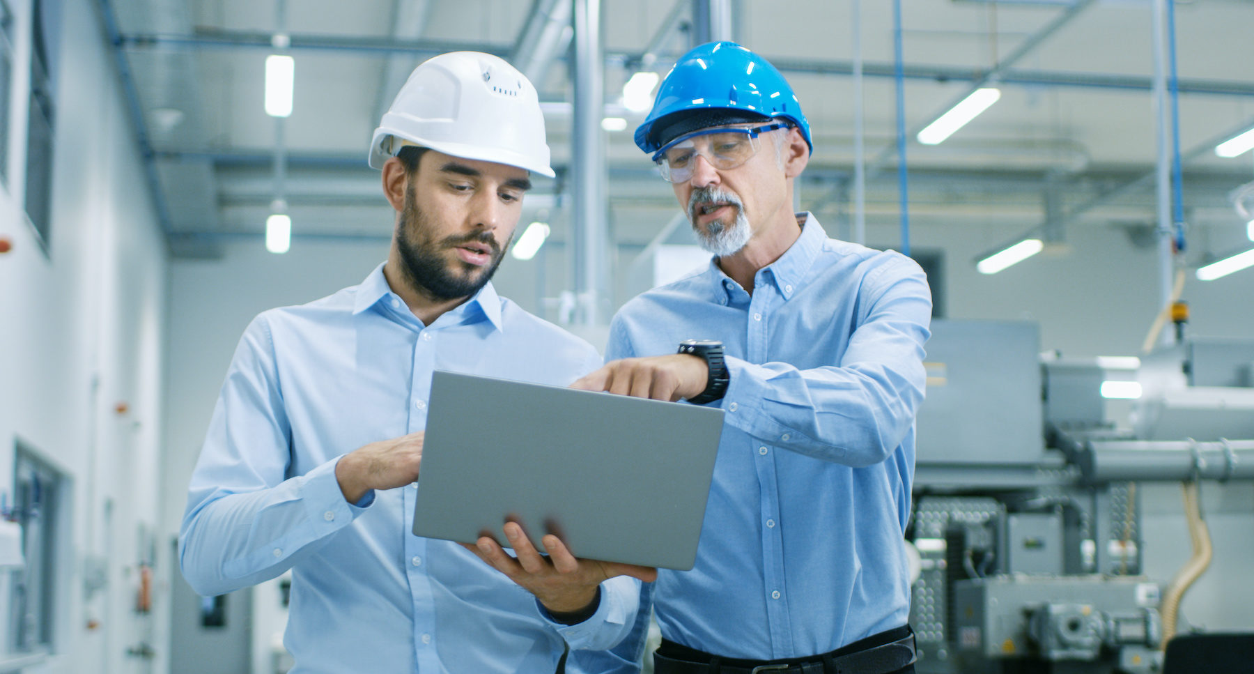 Head of the Project Holds Laptop and Discusses Product Details with Chief Engineer while They Walk Through Modern Factory.