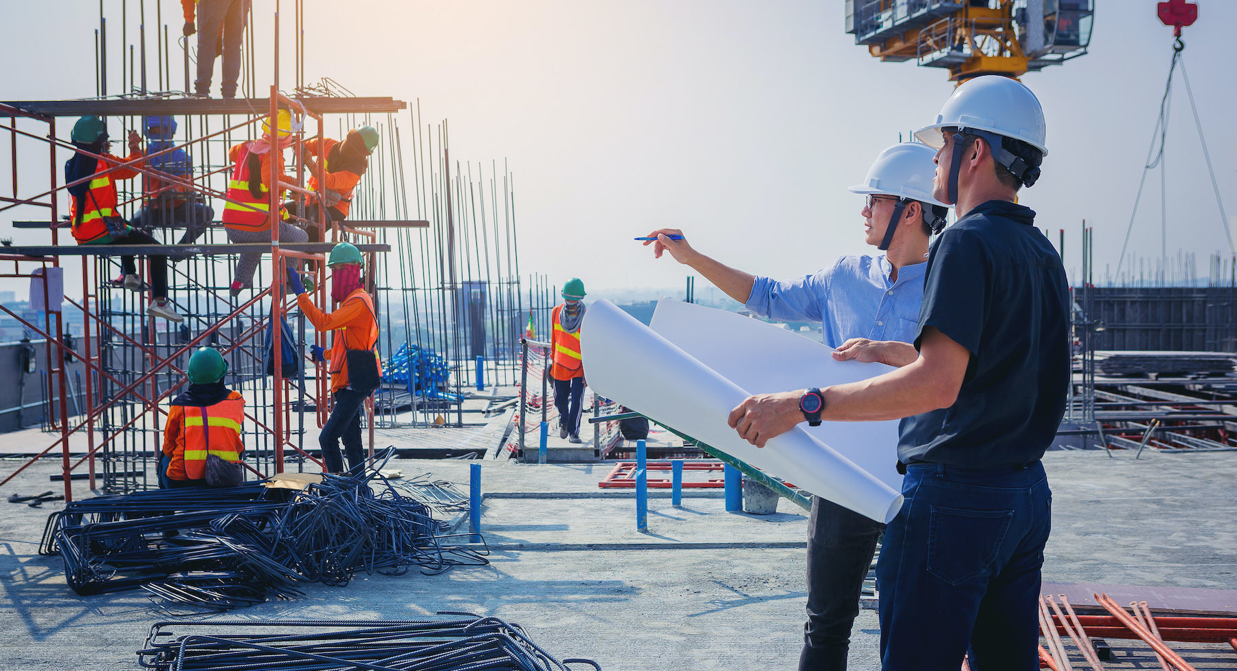 Structural engineer and architect working with blueprints discuss at the outdoors construction site.