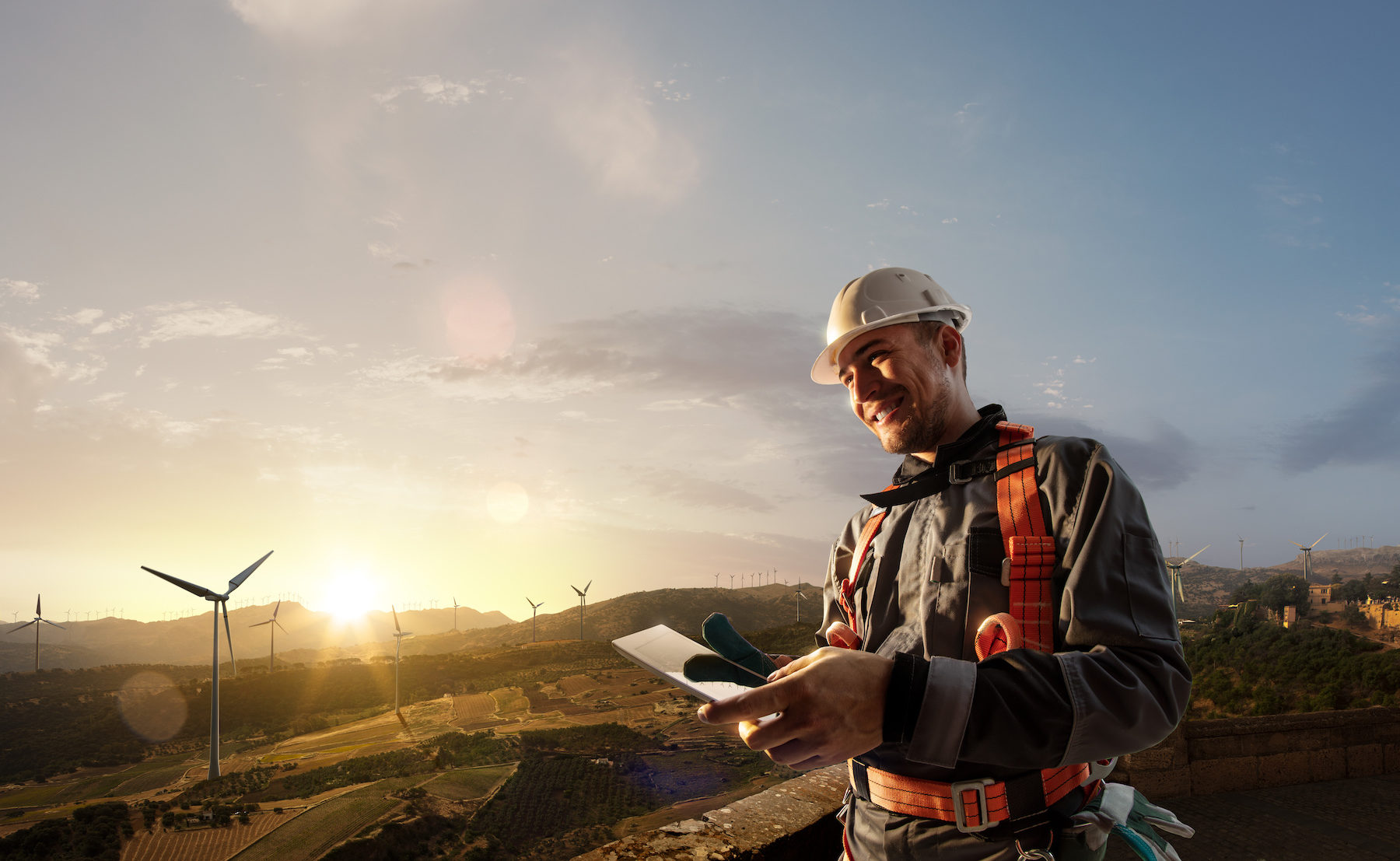 Happy engineer planning new project. He standing a top mount and looking in tablet