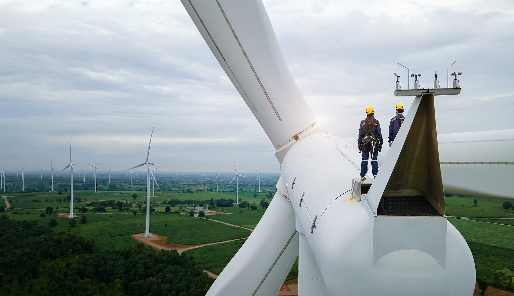 Engineers standing on top of wind turbine